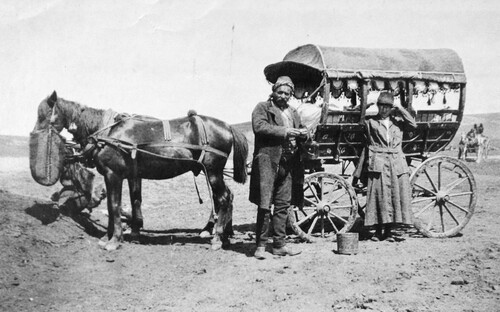 A relief worker and a driver stand at a decorated araba with tasseled fringes. c. 1919-1922.