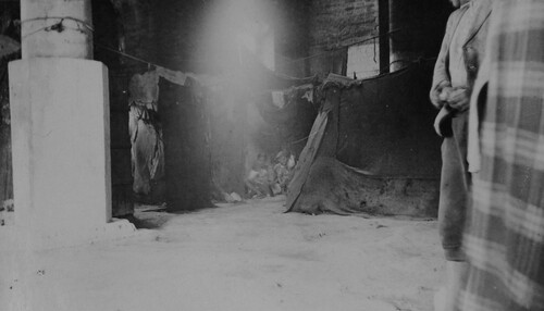 Families live behind hung blankets in a bare shell. Salonica, c. 1922-1923.