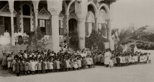 More than a hundred children gather before the main building of the Birds' Nest orphanage, 1924.