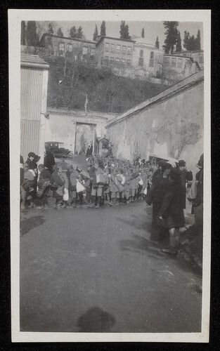 Orphan column with bundles passing a US-flag gate, 1920s