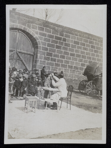 Doctor treating a child's eyes outdoors, Caucasus, 1920s