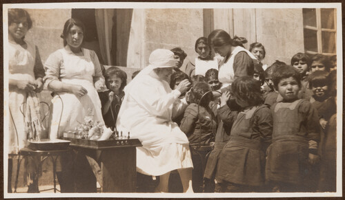 Ellen M. Norton treats one child while dozens wait. Aleppo, 1922.